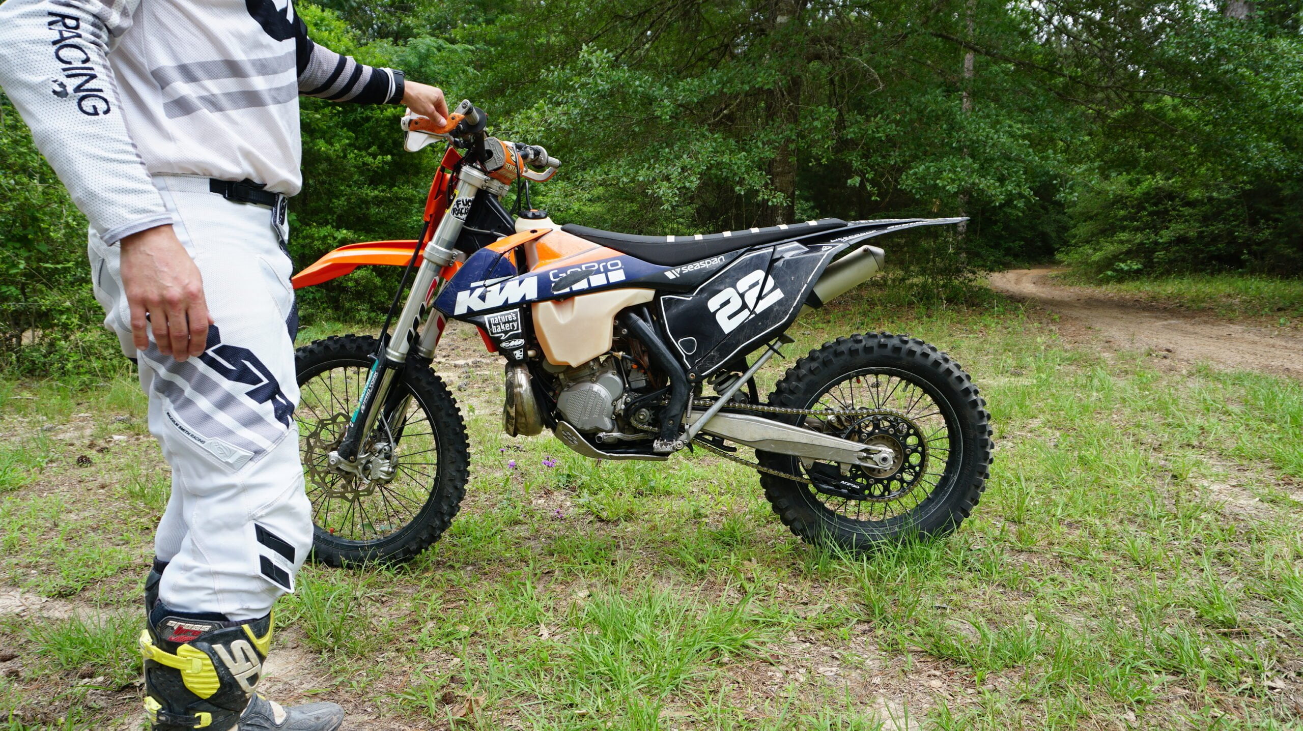 Man holding a dirt bike with one hand from the handlebar for measuring static or free sag