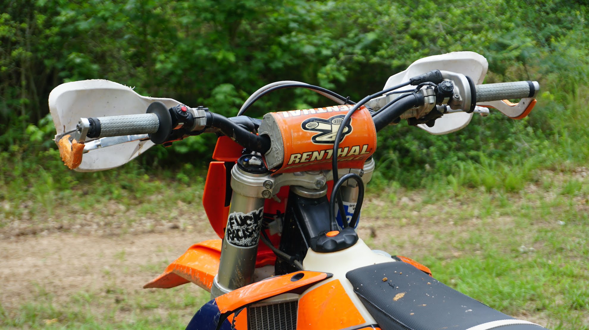 Rider side of dirt bike handlebars with handlebar pad, grips, levers and handguards
