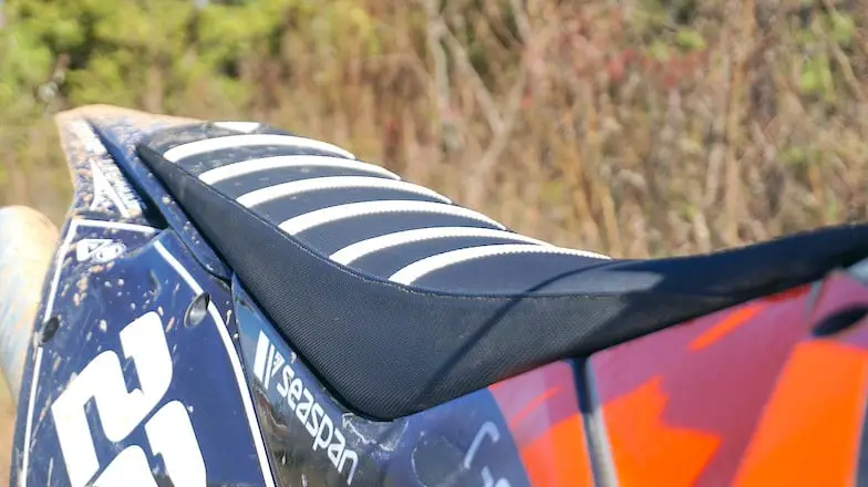 A close-up view of a black dirt bike seat with white ribs