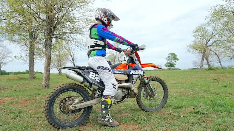 A man sitting on a dirt bike with both hands on the handlebar and right foot touching the ground