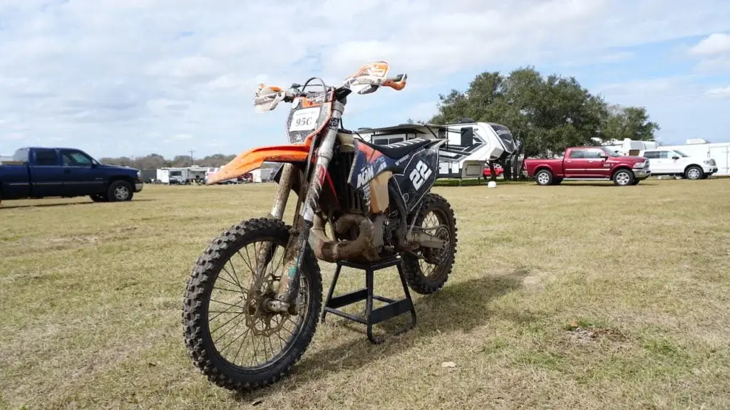 Dirt bike on a center stand with trucks and trailers on the background