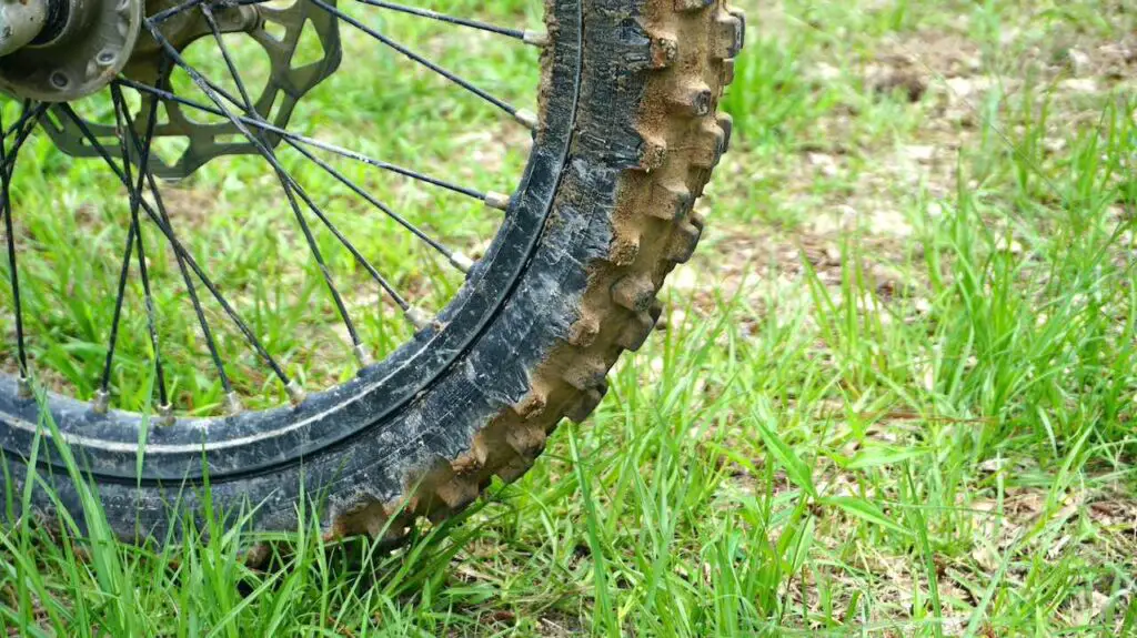 Dirty dirt bike tire of a dirt bike on a grassy ground