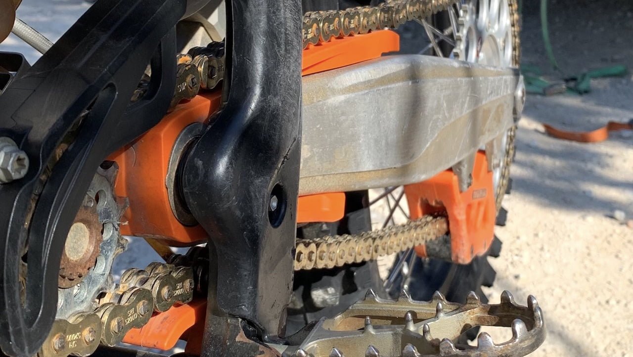 An orange chain guide and slider kit installed on a dirt bike