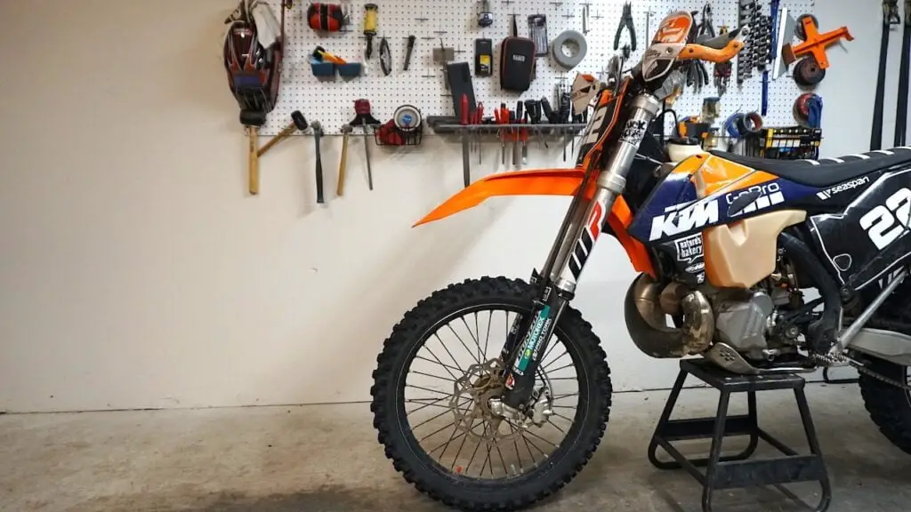 Dirt bike standing in a garage on a center stand ready for wheel bearings to be replaced