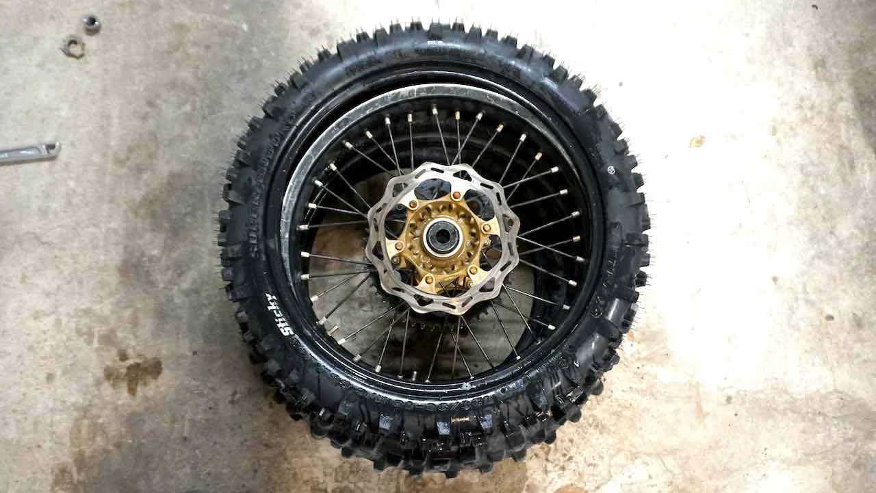 A wheel placed inside a new dirt bike tire but not yet properly installed