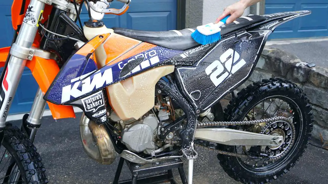 Dirt bike being scrubbed with a brush and soap