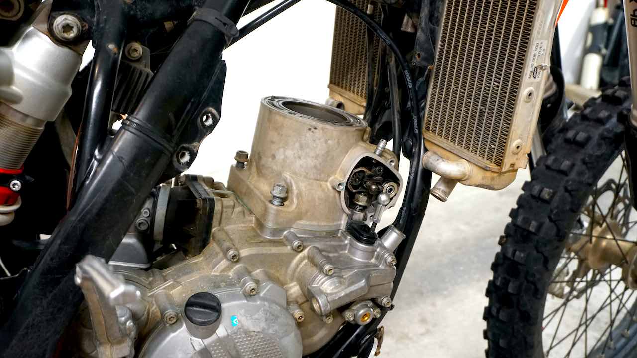 A dirt bike motor with all four cylinder base nuts loosen
