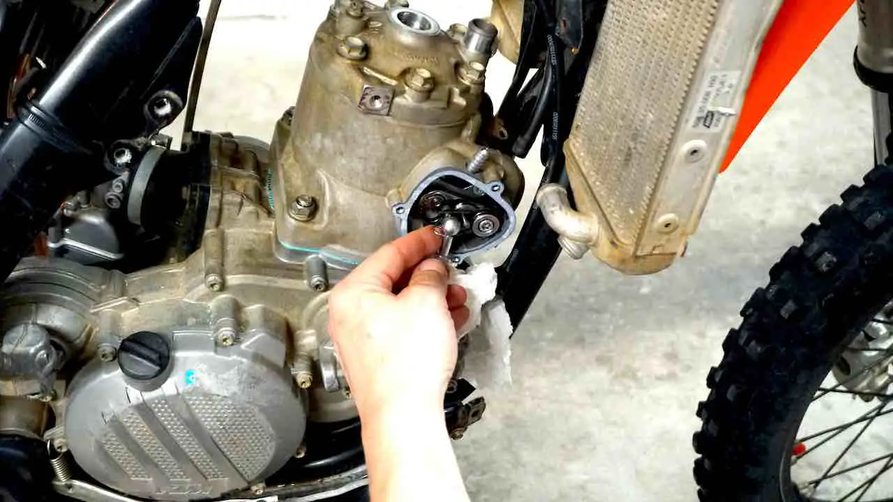 A hand inserting a circlip in the power valve push rod while performing a 2 stroke top end rebuild