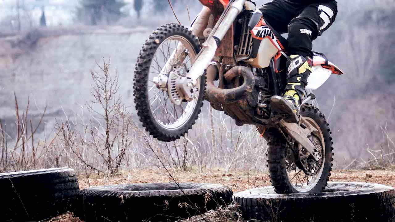 Dirt bike riding over truck tires with the front wheel in the air