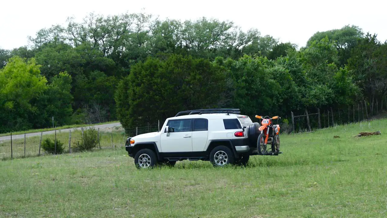 SUV with a dirt bike loaded onto a hitch carrier ready for transport