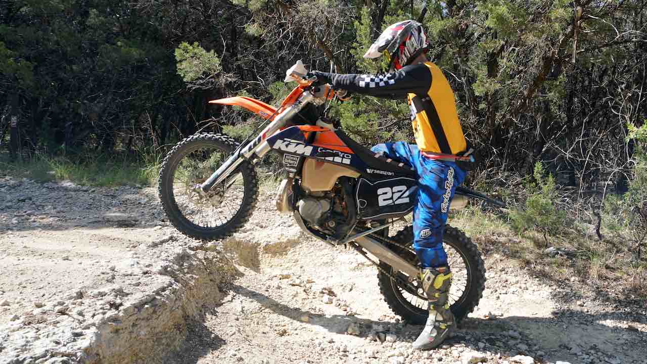 Rider using the dirt bike clutch friction point to lift the front end into a wheelie