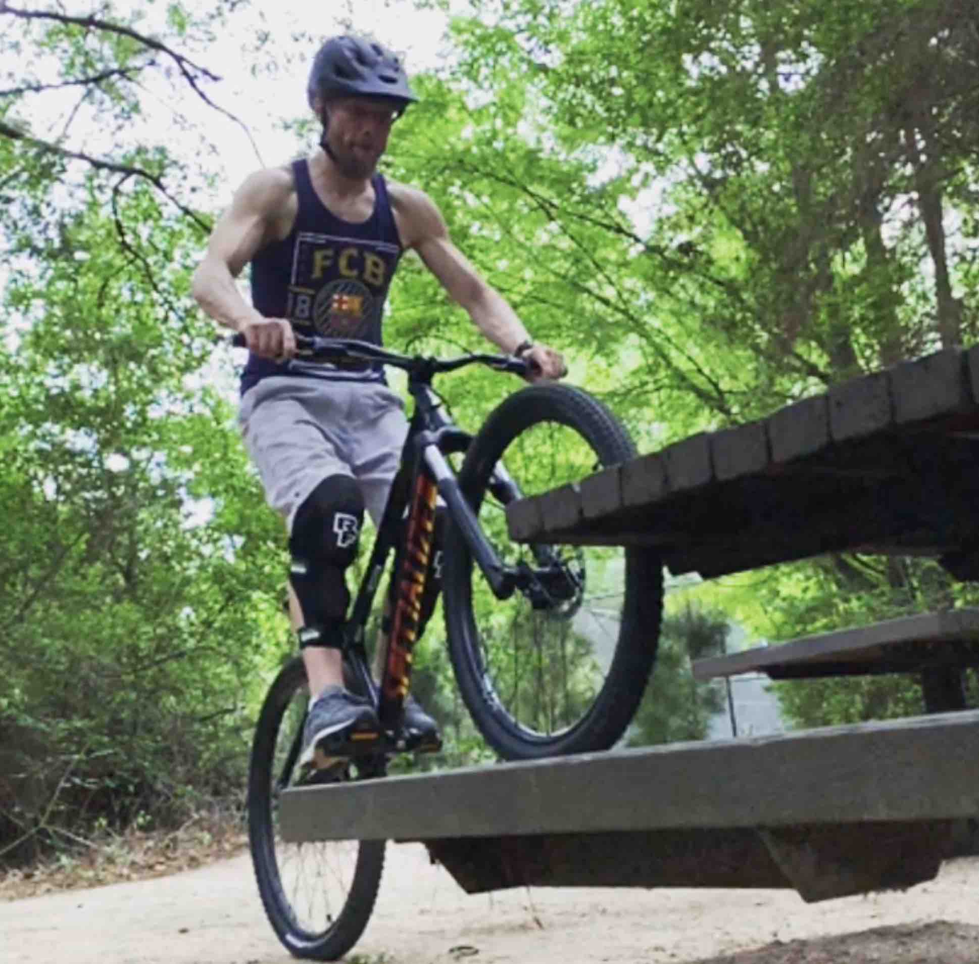 Person standing on a bicycle practicing against a picnic table