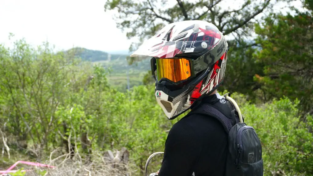 Dirt bike rider with a helmet and goggles on looking at scenery forest views