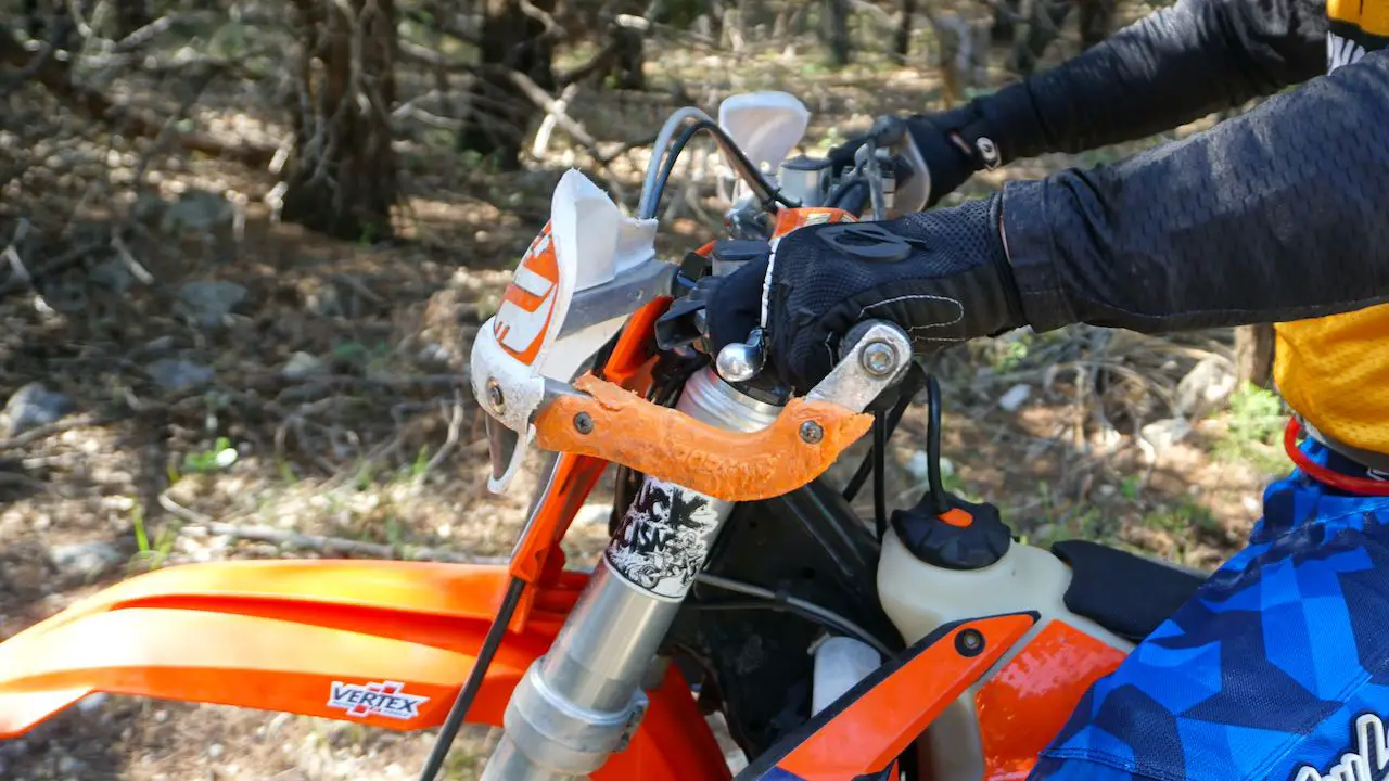 A dirt bike with a rider gripping the handlebar with gloves on