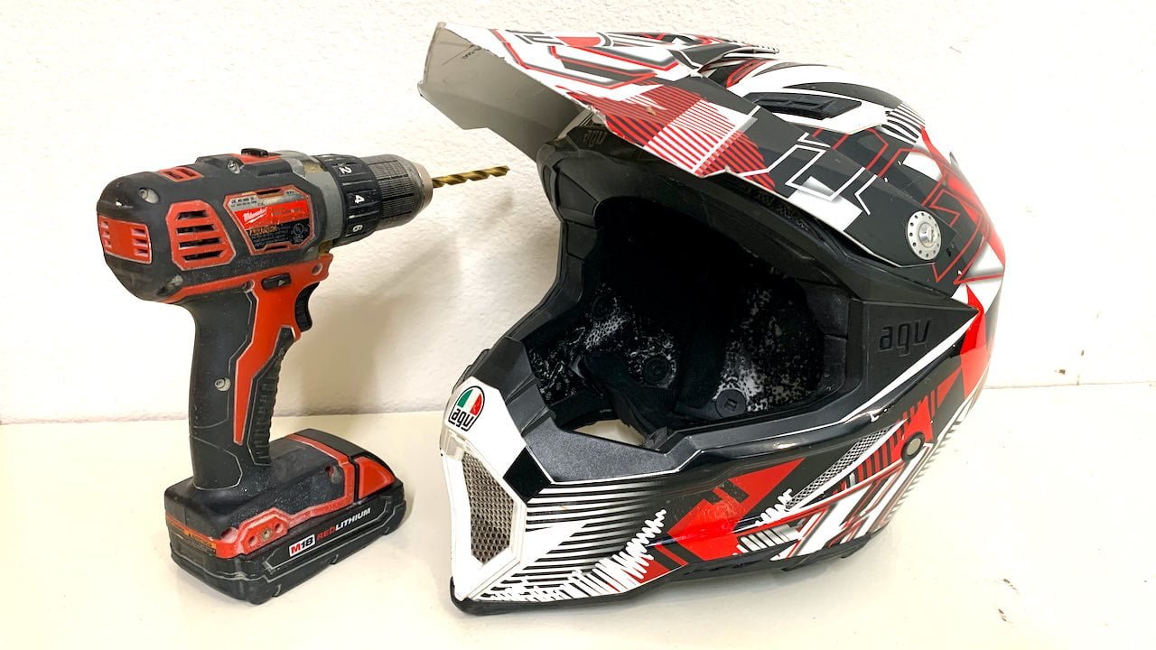 Dirt bike helmet for hot weather with a drill next to it on a table