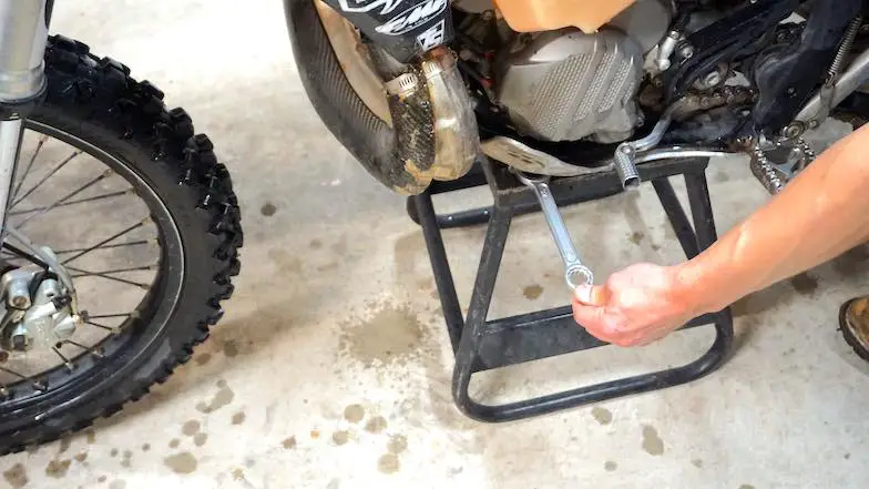 Placing a wrench under the skid plate to lift front wheel off the ground