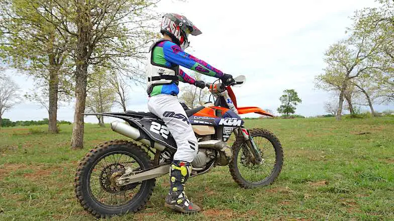 Dirt bike rider testing the dirt bike size and seat height with one foot on the ground