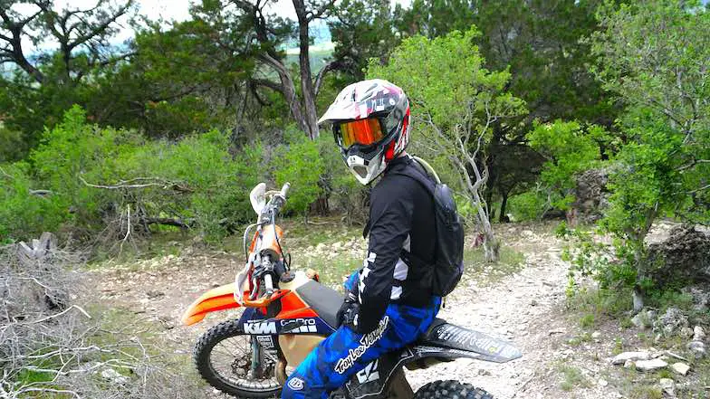 Enduro riding at mountains, rider looking back sitting on a dirt bike