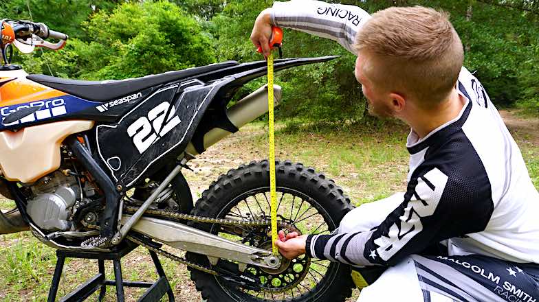 Rider measuring sag on a dirt bike with a tape measure