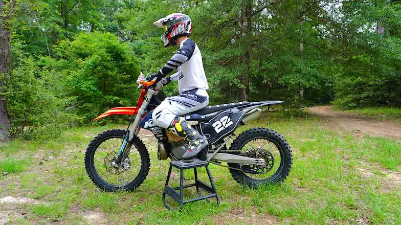 Rider measuring sag on a dirt bike with a tape measure