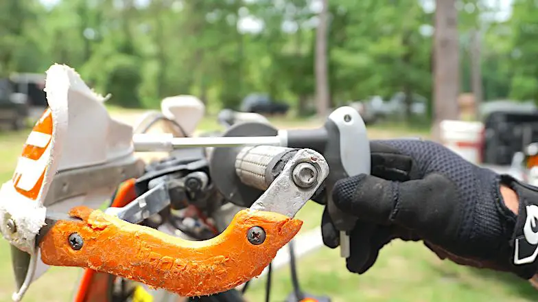 Hand holding a T-handle tool level on top of the grip pointing forward on top of clutch lever