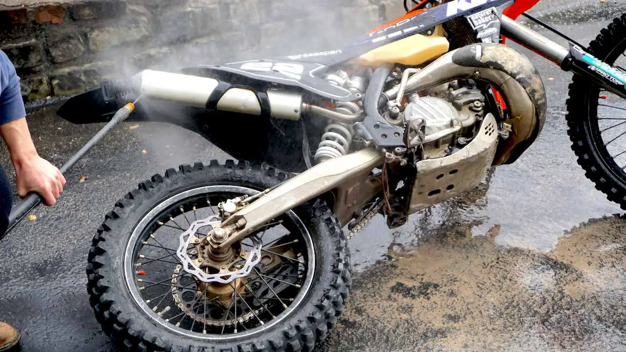 Dirt bike laying on the ground while being washed