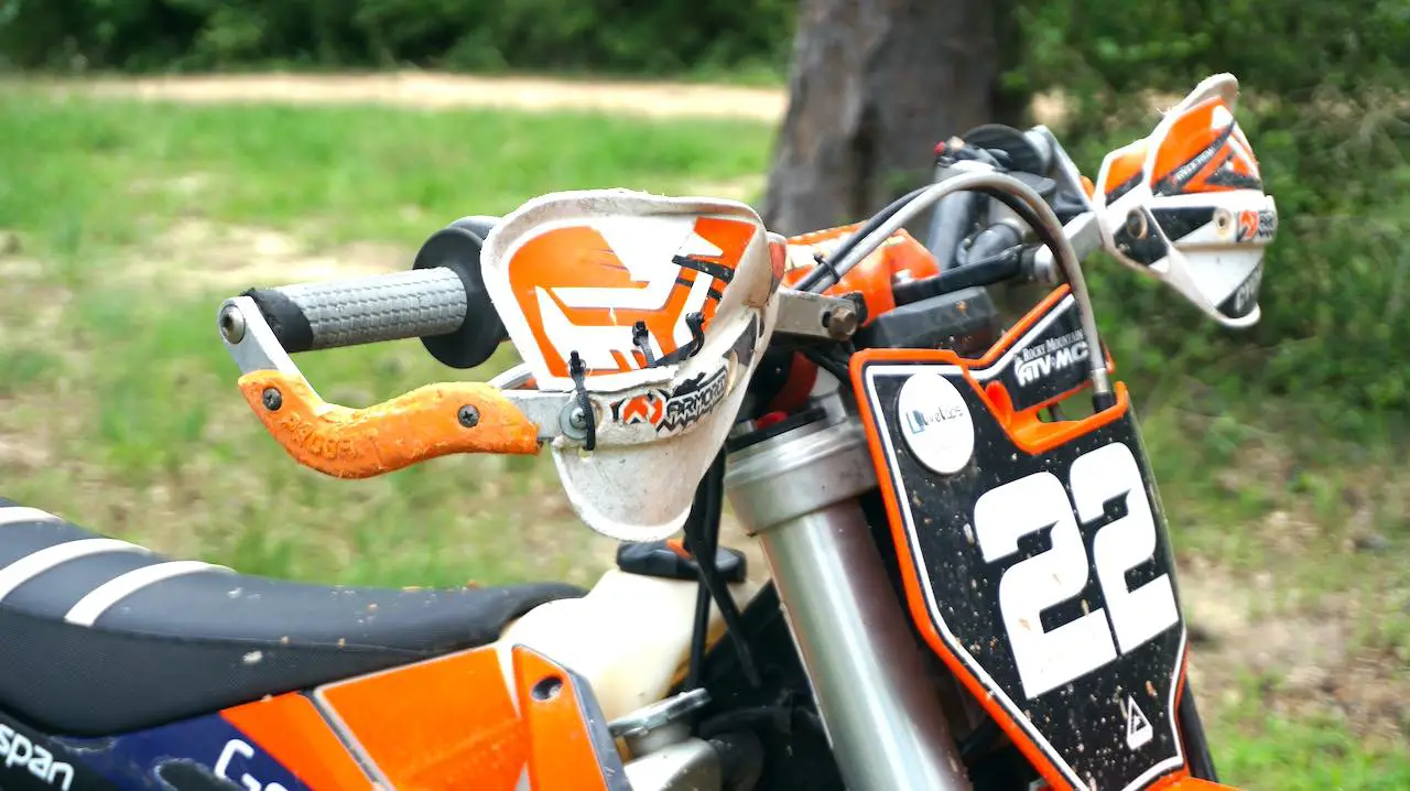 Dirt bike handlebar with dented dirt bike handguards that have been repaired with zip ties