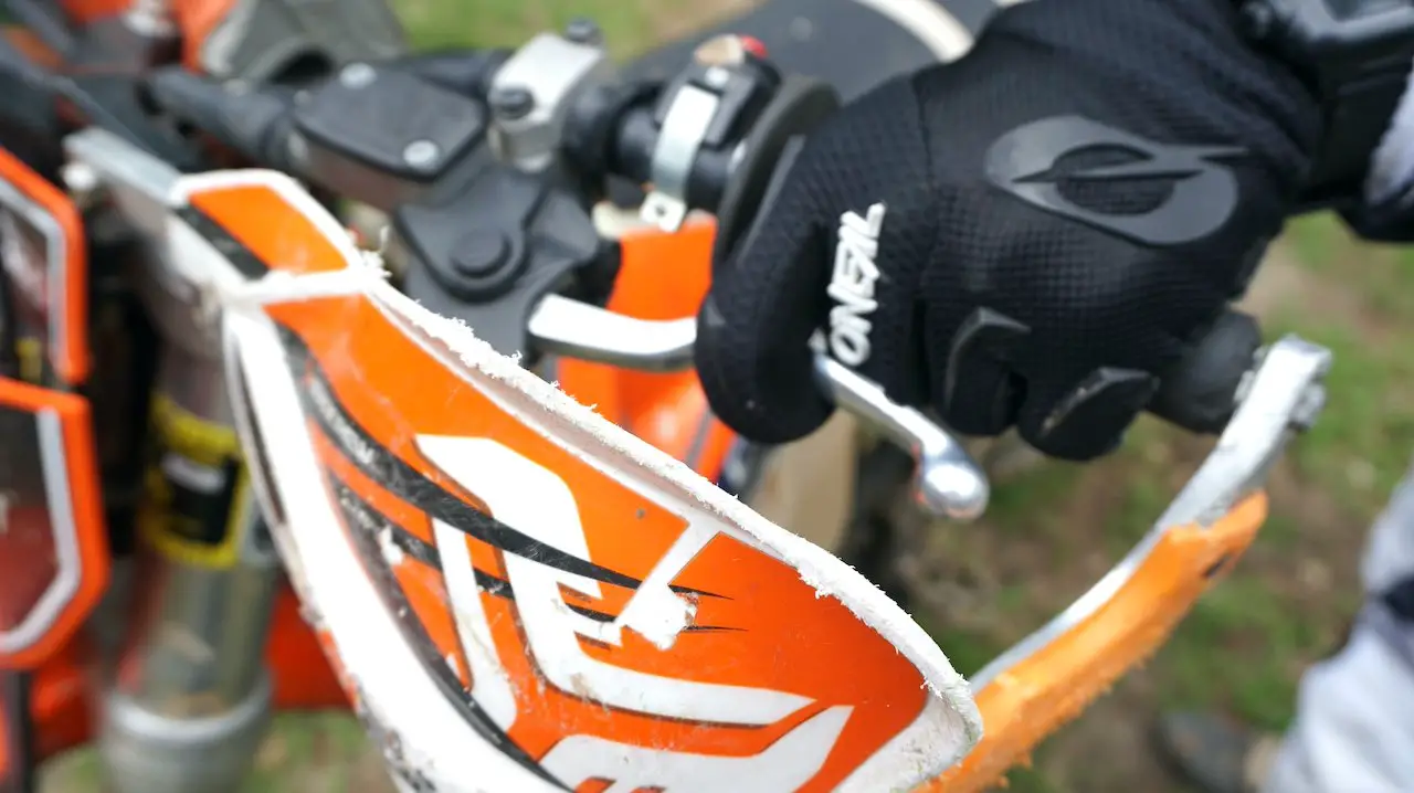 Hand gripping the left handlebar of a dirt bike with index finger around the lever