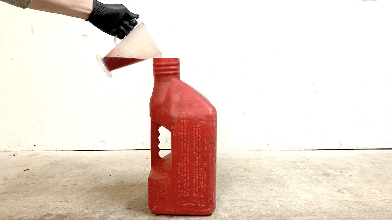Pouring 2 stroke oil into a mixing gas jug using a 2 stroke oil mixing cup