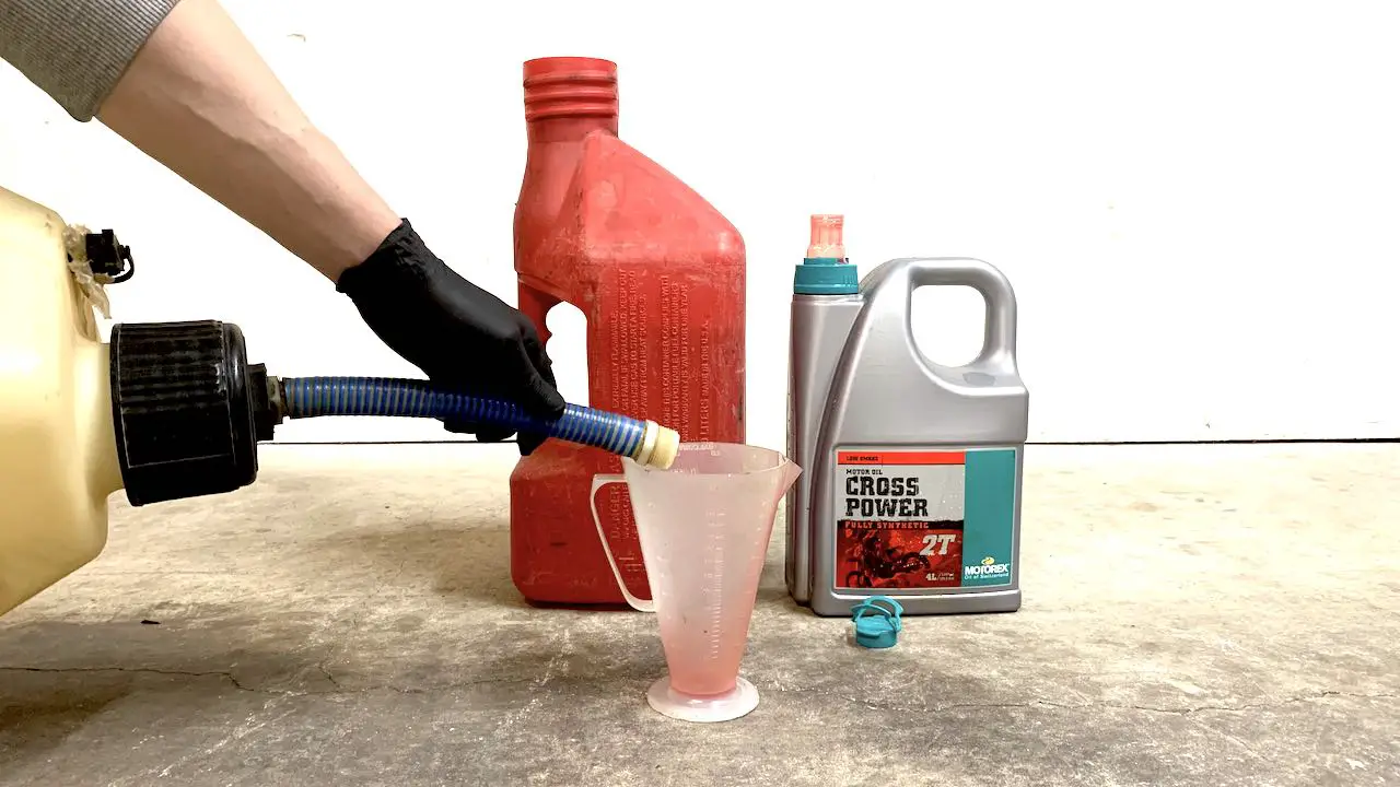 Pouring fresh gas into a 2 stroke oil mixing cup