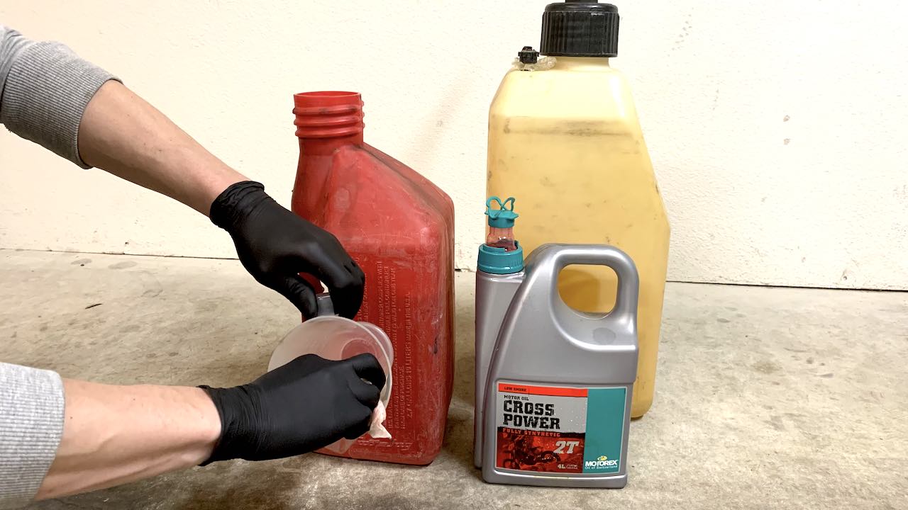 Wiping a 2 stroke oil mixing cup clean with a paper towel