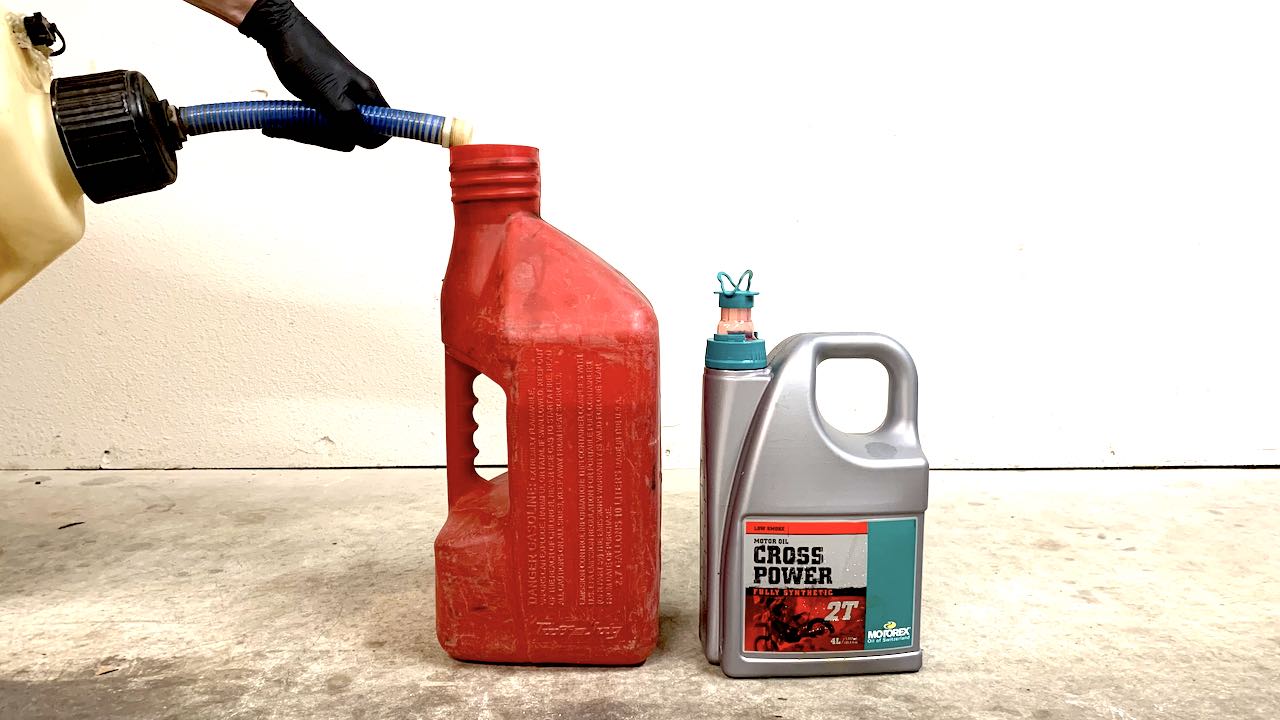 Pouring fresh gas into a gas mixing jug with 2 stroke oil ready for mixing