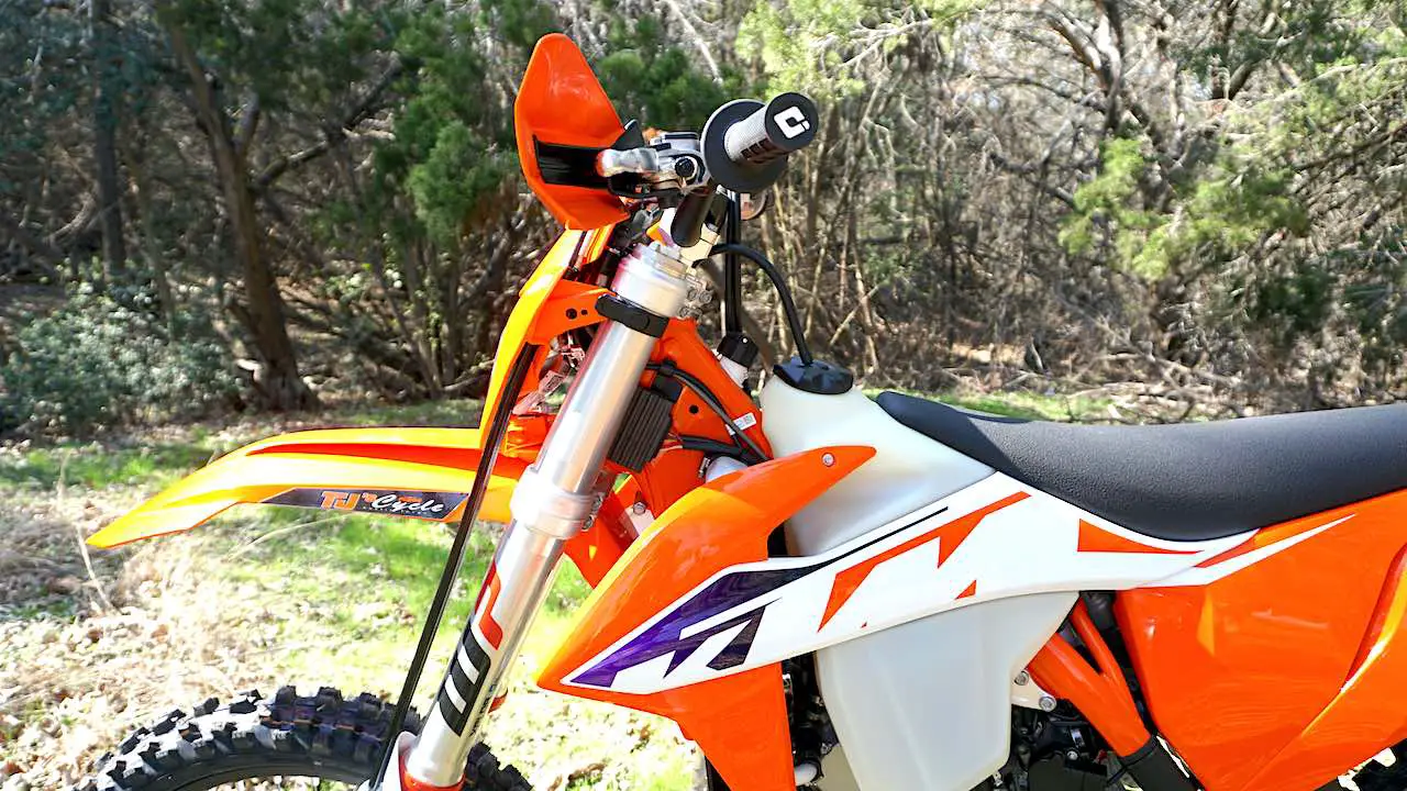 New KTM 300 ready for setting up the dirt bike suspension, sitting on a center stand against a green field