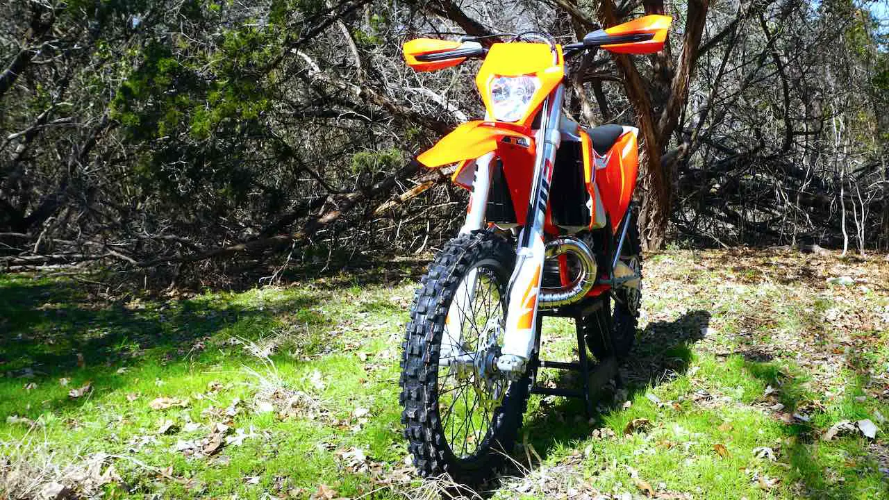 2023 KTM XC-W 300 on a center stand against a forest. This dirt bike weighs 228 lbs or 103.4 kg.