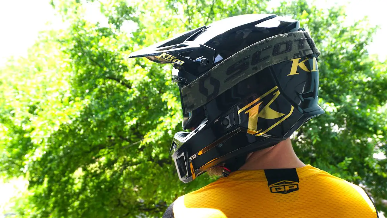 KLIM F3 Carbon and goggles against a green background